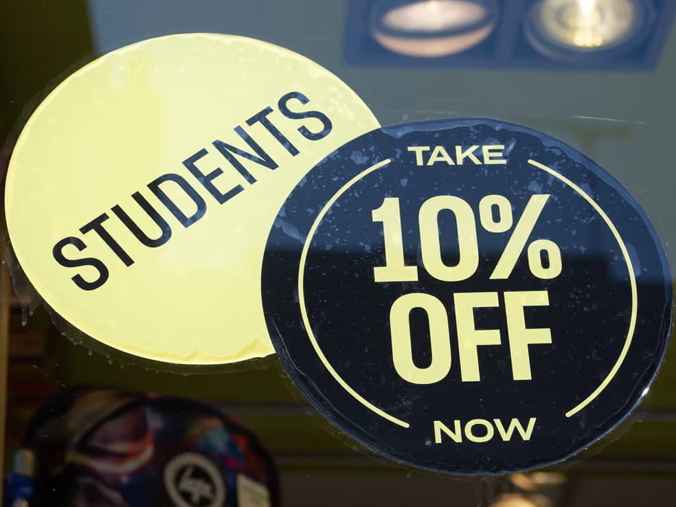 Two stickers in a shop window reading STUDENTS and TAKE 10% OFF NOW